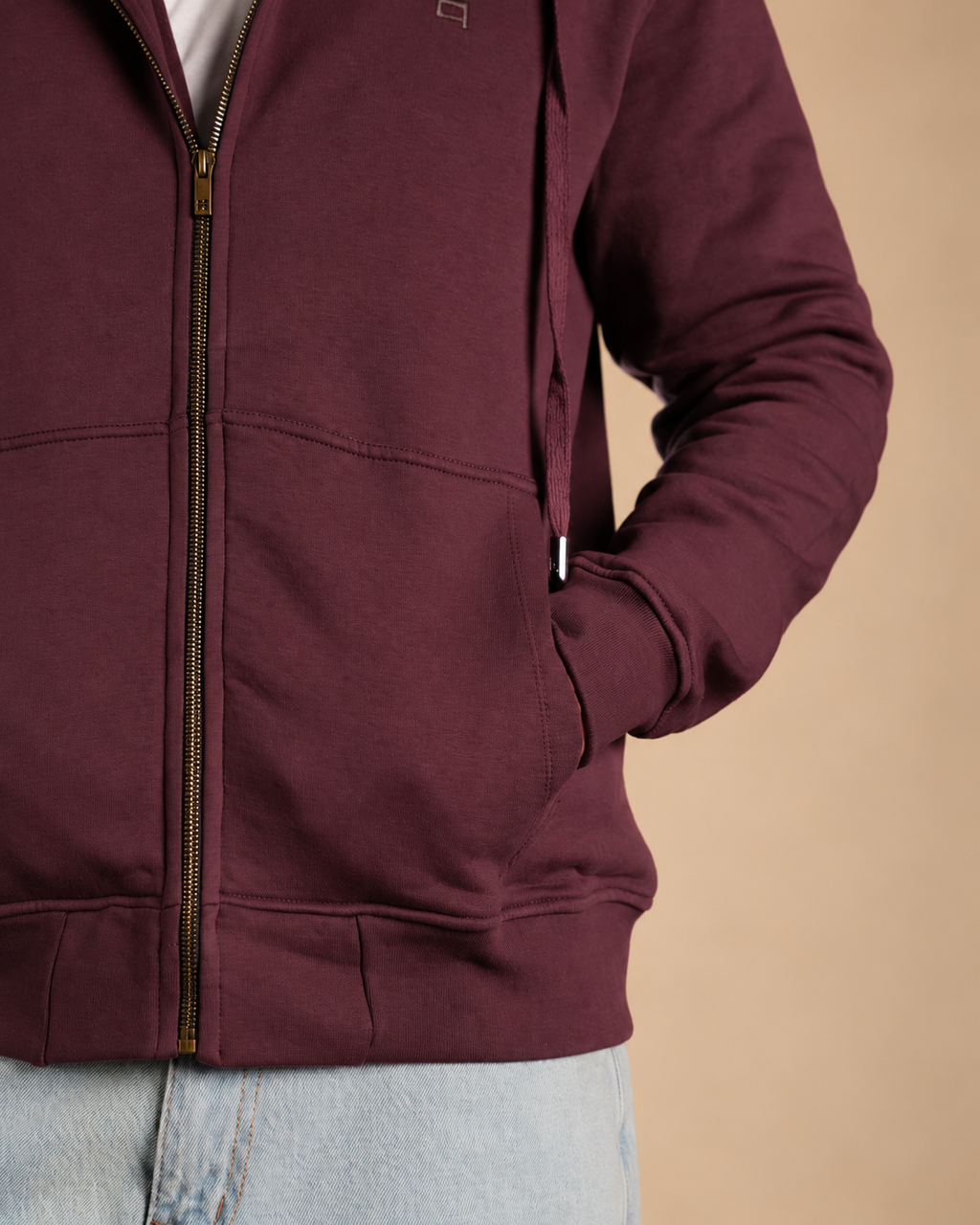 Stabraq High Neck Melton Zipper in burgundy, close-up of the pocket, sleeve and hem on a beige studio background