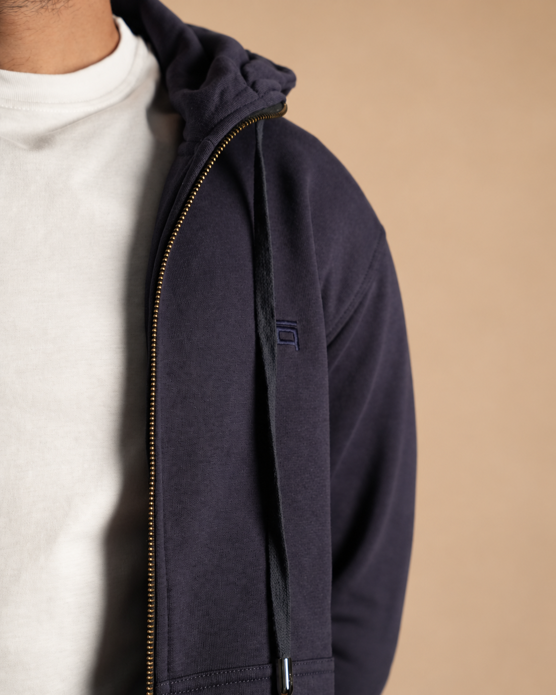 Stabraq High Neck Melton Zipper in navy blue, close-up of chest embroidery and drawstring on a beige studio background