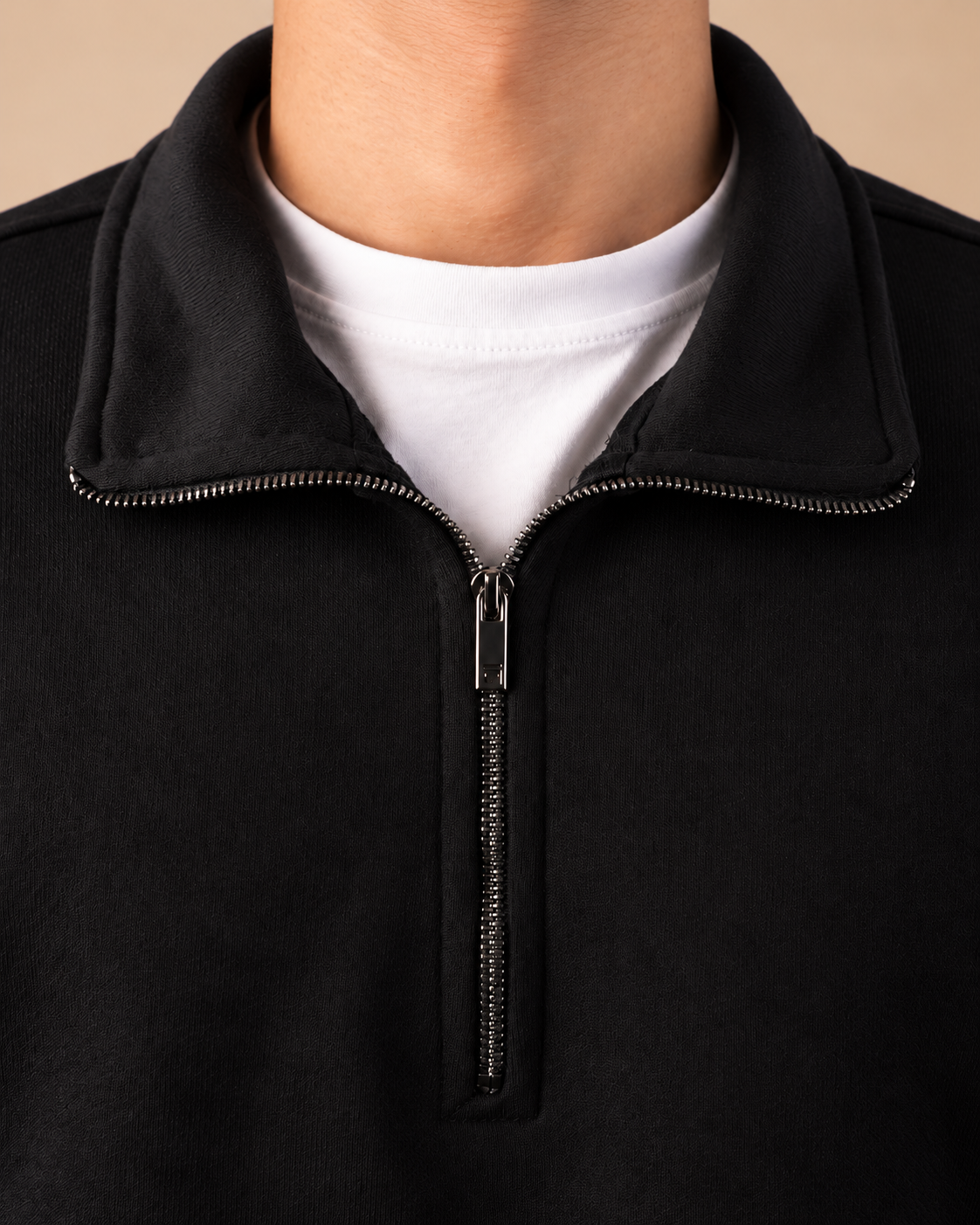 Stabraq Black Quarter Zipper, tight close-up of collar, zipper and fabric on a beige studio background