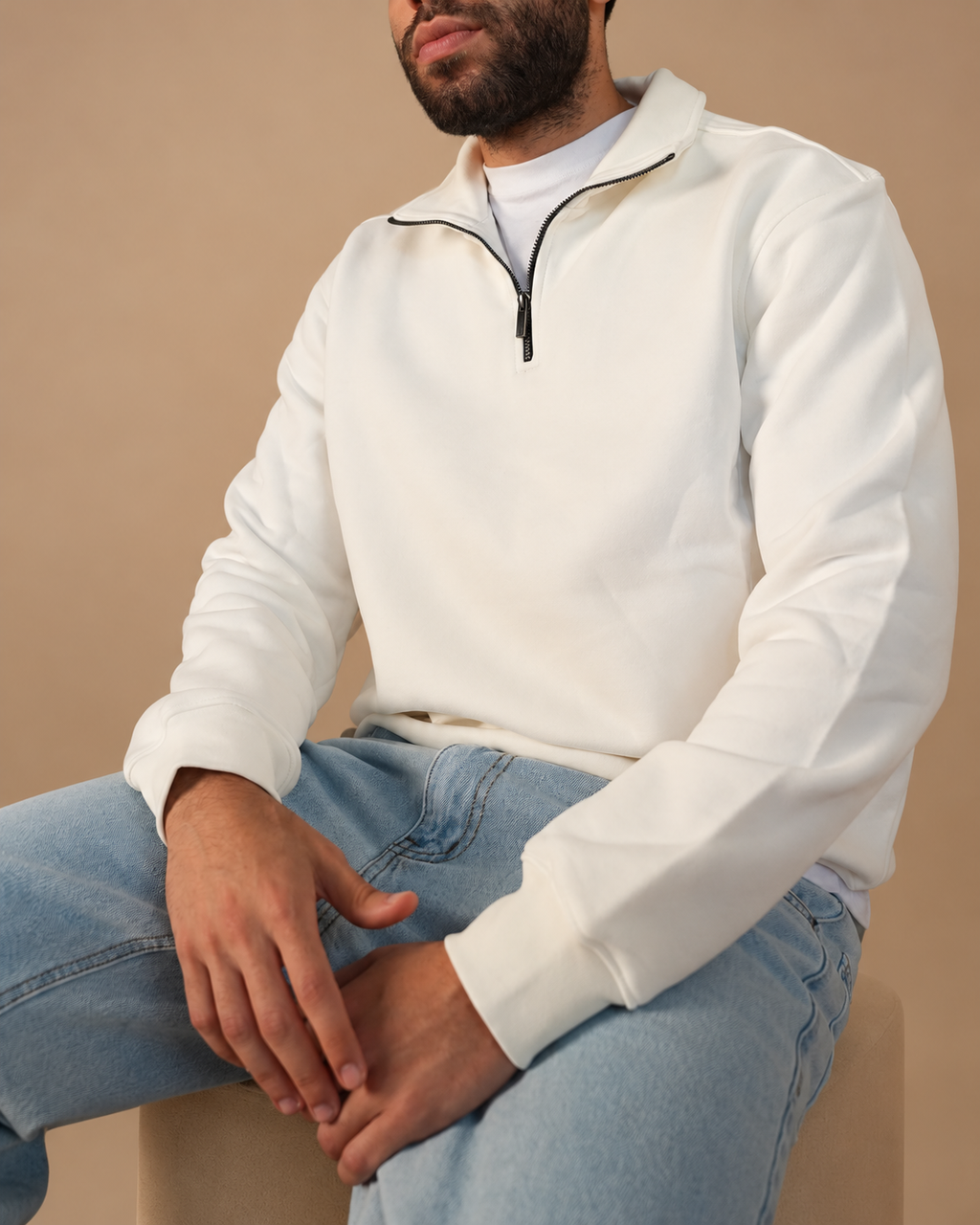 Stabraq Off White Quarter Zipper, seated upper-body view with lower-face crop on a beige studio background