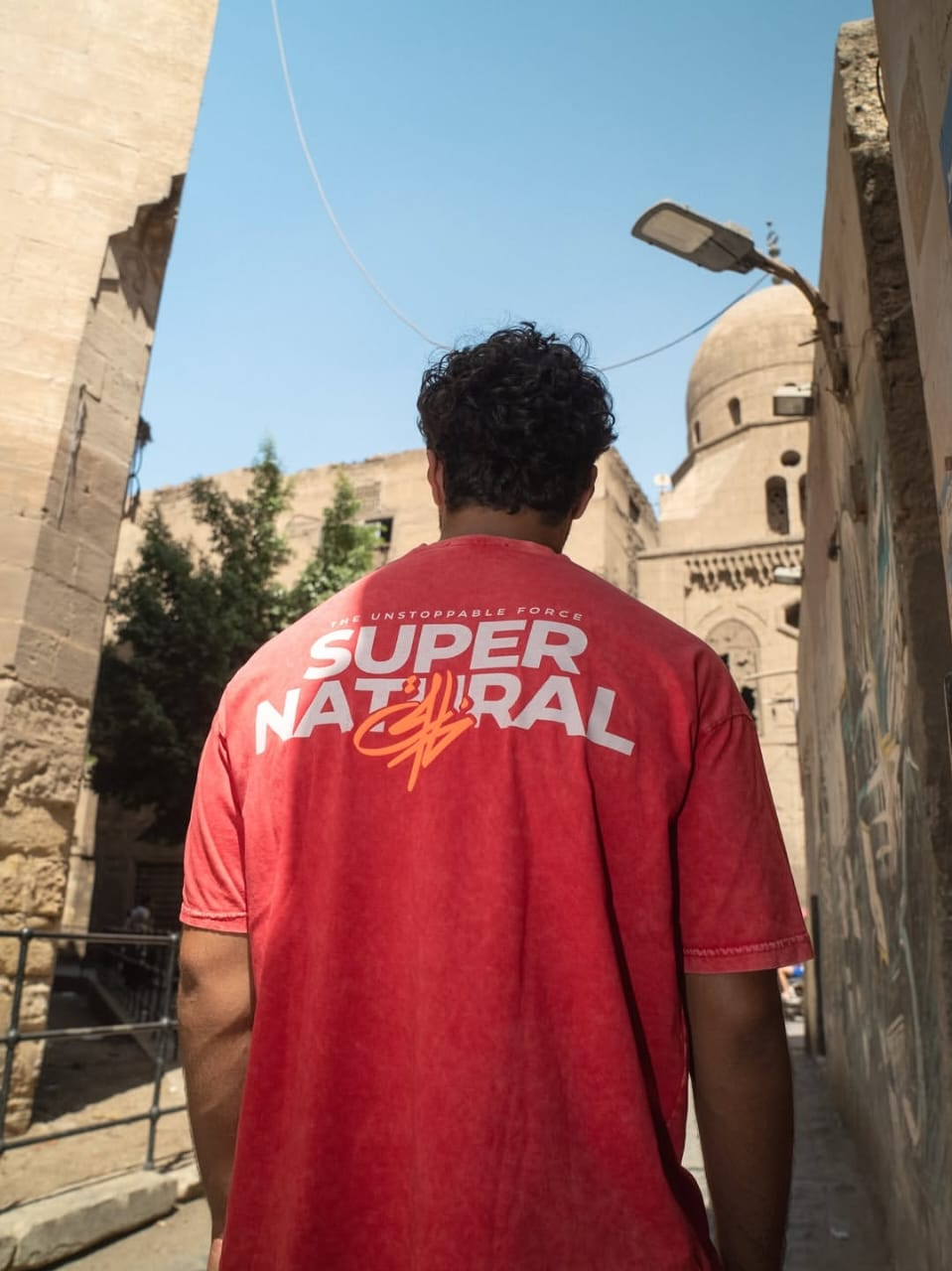 Back print of the red Stabraq Super Natural graphic T-shirt photographed outdoors
